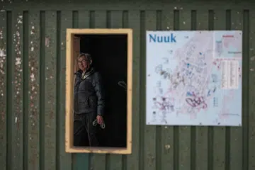 Seorang individu menunggu di dalam hentian bas yang ditandai dengan papan tanda laluan di Nuuk, Greenland, pada 22 Januari 2026.