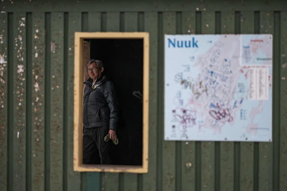 Seorang individu menunggu di dalam hentian bas yang ditandai dengan papan tanda laluan di Nuuk, Greenland, pada 22 Januari 2026.