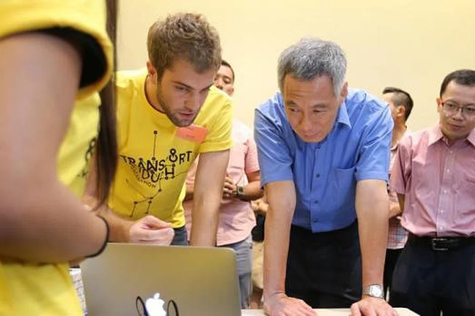 APLIKASI UNTUK GOLONGAN KHAS: Encik Lee mendengar penjelasan mengenai aplikasi 'Come Ride With Me' daripada anggota pasukan, Encik Thomas Dohm (dua dari kiri). Aplikasi itu menghubungkan pengguna berkeperluan khas dengan sukarelawan yang dapat membantu perjalanan pengguna ke destinasi mereka. - Foto THE STRAITS TIMES
