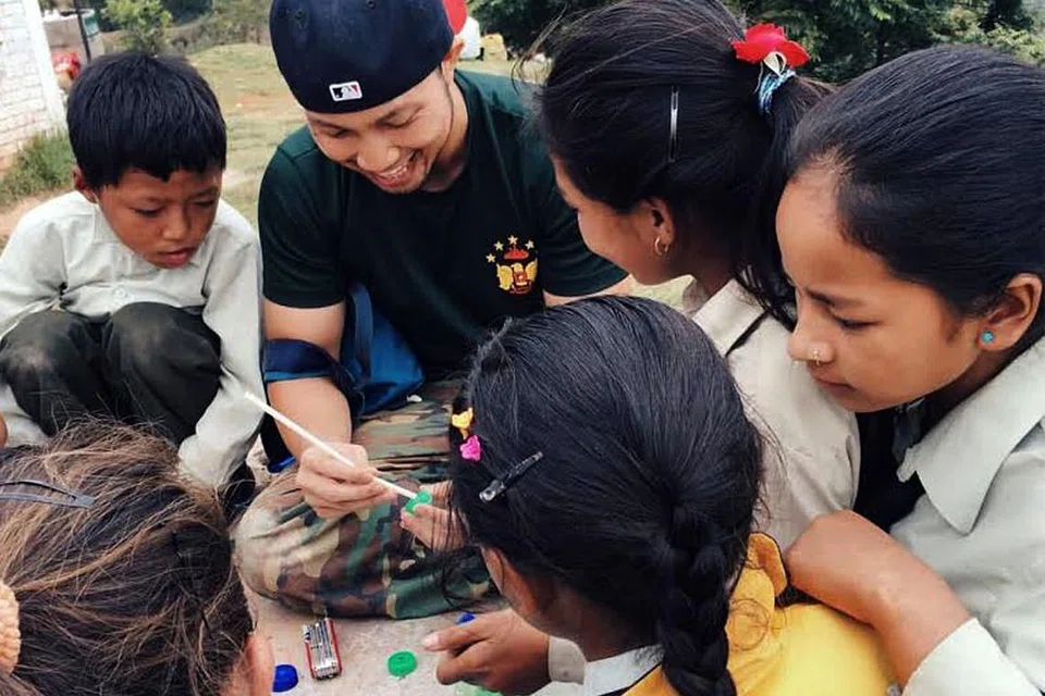 DAHAGAKAN ILMU: Pelajar Nepal mengerumini Encik Irfaan (bertopi) sementara beliau mengajar mereka cara membina sebuah kereta menggunakan penutup botol yang terpakai. - Foto SYAHIRAH AFIFAH ABU BAKAR