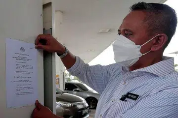 PERIKSA NOTIS: Encik Mohd Hairul memeriksa notis pemberitahuan KPDNHEP mengenai peraturan penjualan minyak petrol kepada kenderaan asing yang ditampal di sebuah kedai minyak di Tampoi, Johor. - Foto NSTP