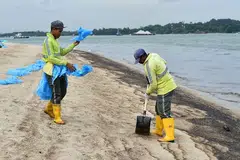 Kontraktor NEA daripada Ramky Cleantech Services Pte Ltd membersihkan pasir daripada kesan minyak di Pantai Changi pada 5 Jan. 