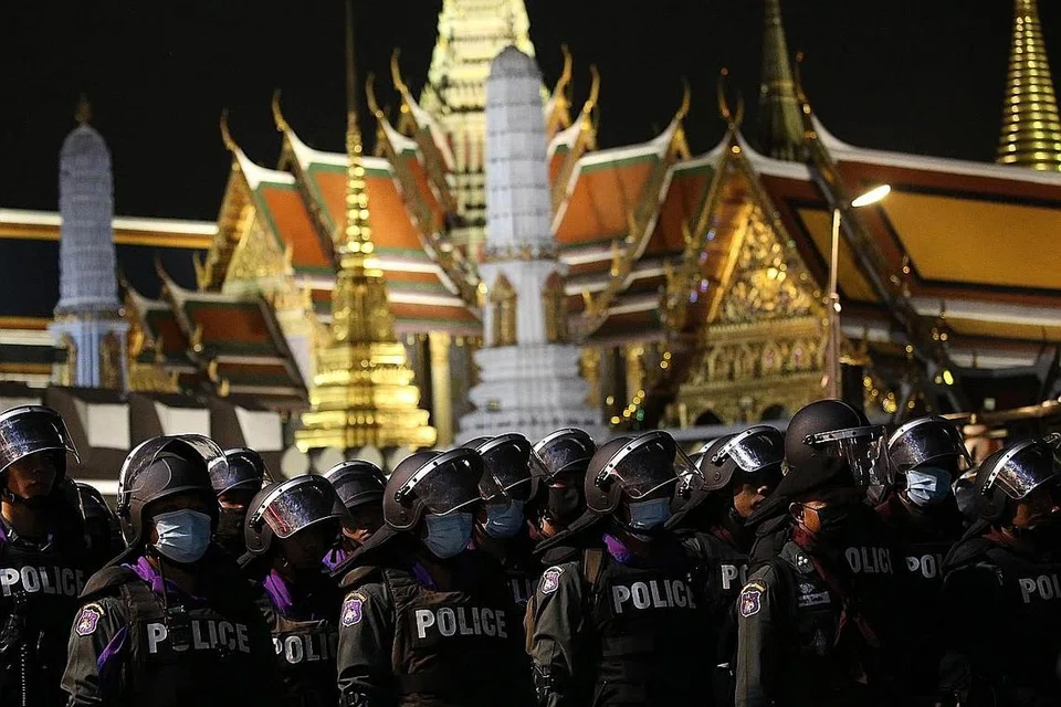 KAWAL ISTANA: Pasukan antirusuhan polis Thailand berkawal di depan kawasan Istana Besar di Bangkok sedang kumpulan penunjuk perasaan berusaha mendekati bangunan itu untuk memberi surat permintaan kepada pihak istana. - Foto EPA-EFE