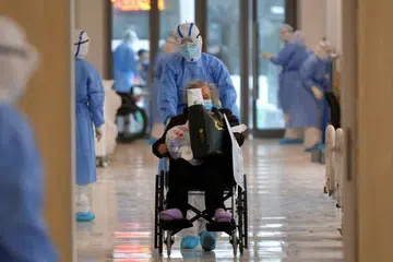 Seorang pekerja perubatan menolak seorang pesakit berkerusi road di sebuah hospital di Wuhan, China pada 10 Februari 2020.