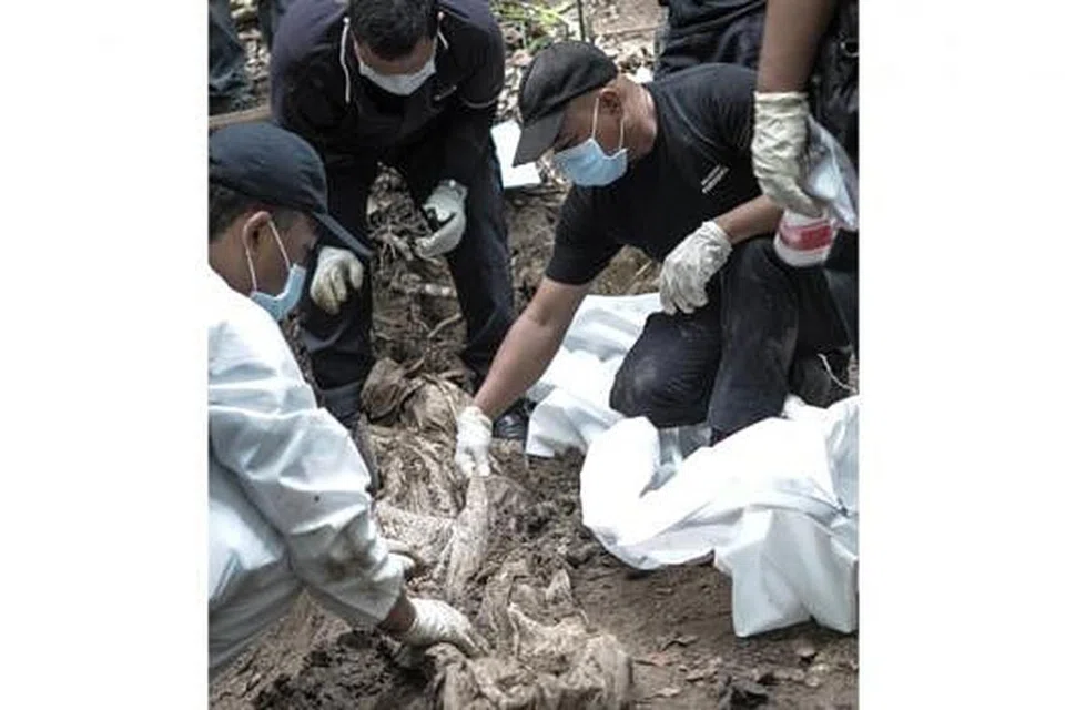 SISA MAYAT: Anggota pasukan forensik Polis Diraja Malaysia menggali kubur yang ditemui di kawasan kem pendatang asing di Bukit Wang Burma, Perlis. - Foto AFP