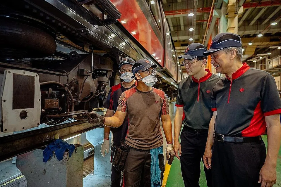 SUMBANGAN PEKERJA: Kakitangan penyelenggaraan SMRT menunjukkan Encik Seah Moon Ming (paling kanan) dan Encik Ngien Hoon Ping (dua dari kanan) salah satu projek Kaizen mereka - inisiatif asas SMRT menjadikan proses kerja lebih selamat dan cekap - di Depoh Kim Chuan yang juga depoh kereta api bawah tanah terbesar di dunia. - Foto-foto SMRT