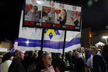 Orang ramai mengangkat sepanduk yang memaparkan gambar, Oded Lifshitz, dan anggota keluarga Bibas, beberapa jam selepas kumpulan Palestin, Hamas, menyerahkan mayat yang didakwa mayat empat tahanan tersebut, pada 20 Februari 2025.