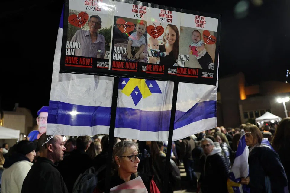 Orang ramai mengangkat sepanduk yang memaparkan gambar, Oded Lifshitz, dan anggota keluarga Bibas, beberapa jam selepas kumpulan Palestin, Hamas, menyerahkan mayat yang didakwa mayat empat tahanan tersebut, pada 20 Februari 2025.