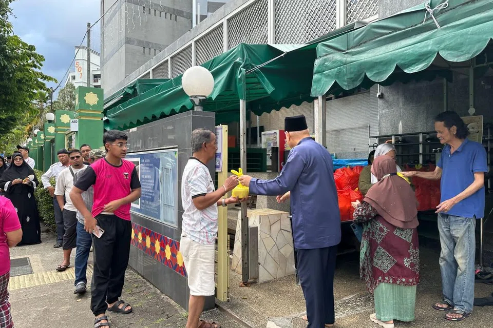 Pengerusi Eksekutif Kanan, Ustaz Mohamed Ali Atan (tiga dari kanan, bersongkok) sedang mengagihkan bubur masjid kepada orang ramai, selepas solat Asar. 