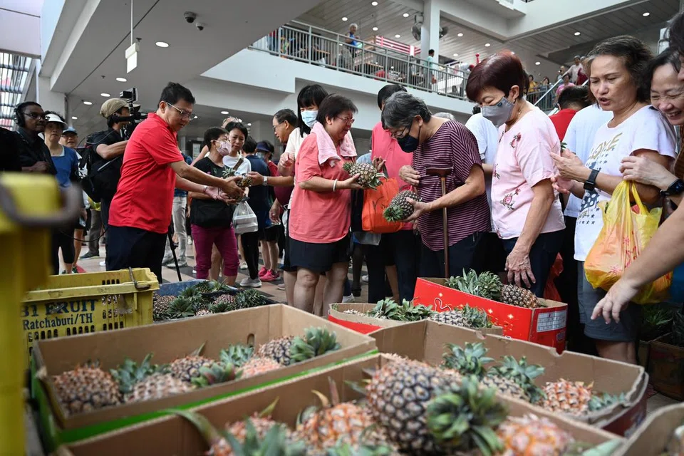 BUAH PERCUMA: Orang ramai yang hadir di Pusat Penjaja Taman Jurong pada pagi Sabtu berpeluang membawa pulang sebiji nanas yang telah diagihkan sebagai meraikan kemenangan Encik Tharman Shanmugaratnam pada Pilihan Raya Presiden 2023. 
