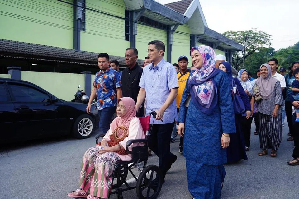 PRIHATIN RAKYAT: Datuk Seri Azmin Ali membantu menolak kerusi roda seorang pengundi di pusat pengundian Sekolah Kebangsaan Klang Gate, Gombak, Selangor, pada pagi Sabtu.