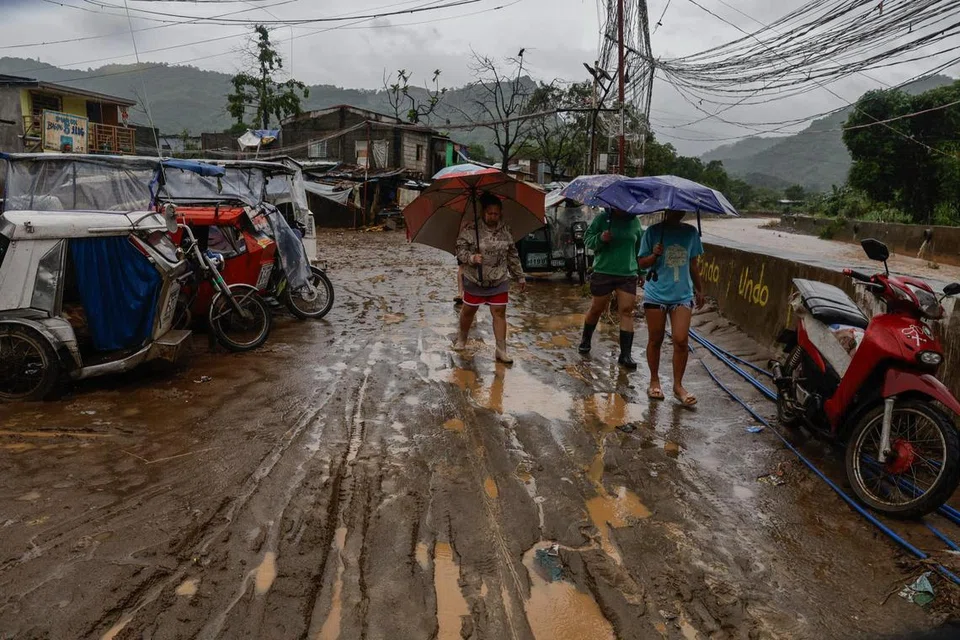 Penduduk berjalan di sepanjang jalan berlumpur selepas banjir surut di sebuah komuniti tepi sungai di Rodriguez, wilayah Rizal yang terletak di timur Metro Manila, Filipina, pada 24 Julai 2025. Biro kaji cuaca Filipina menjangkakan taufan Co-May berada 210 kilometer di barat wilayah Pangasinan di utara Filipina, dengan kelajuan angin 120 kilometer sejam berhampiran pusatnya.