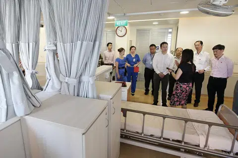 ELAK PESAKIT JATUH: Dr Lam Pin Min (lima dari kanan) mendengar penjelasan tentang operasi huraian pengurusan pencegahan jatuh yang kini sedang diuji di Pusat Penjagaan Orange Valley di Balestier semalam. Sistem itu dapat mengesan pergerakan pesakit atas katil dan akan memaklumkan kepada kakitangan menerusi aplikasi telefon bimbit jika ada pesakit yang bangun dan cuba turun dari katilnya. - Foto BH oleh DARWIS SUNARYO