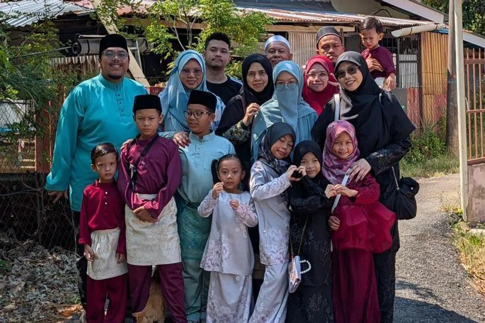 Cik Siti Sarah Abdullah (dua dari kiri) bersama suaminya, Encik Muhammad Takiyuddin Mohd Sabarani (kiri) berlindung di tempat teduh untuk merakam gambar kenangan bersama keluarga ketika pulang beraya ke Alor Setar, Kedah, pada Aidilfitri 