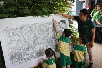 RAIKAN LIMA DEKAD: Timbalan Pengerusi Mandai Park Holdings, Encik Tan Chuan-Jin, bersama kanak-kanak prasekolah yang menulis ucapan sempena ulang tahun ke-50 Taman Haiwan Singapura.