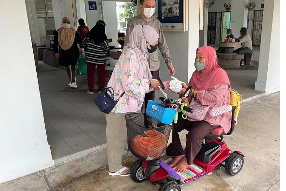 PELUANG BERAMAH MESRA DENGAN PENDUDUK: Cik Selina Salleh (kiri) bersama Ustaz Ruhaizan Abdullah (tengah) bertanya khabar kepada Cik Hasnah Wahab yang menaiki PMD, untuk mengambil bubur di kolong Blok 137 Yishun Ring Road anjuran bersama Jawatankuasa Eksekutif Kegiatan Melayu (MAEC) Chong Pang dan pihak Masjid Darul Makmur. - Foto MASJID DARUL MAKMUR