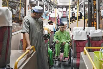 PELUANG BERJEMAAH DI MASJID: Encik Abu Bakar (tengah) menaiki bas mesra kerusi roda yang disewa khas buat jemaah sepertinya. Bas itu membawanya ulang alik dari stesen bas berdekatan rumahnya ke Masjid Maarof. - Foto BH oleh KHALID BABA