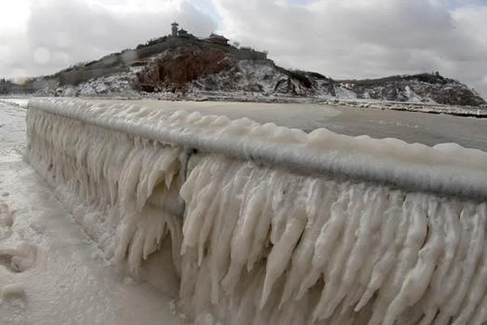 SEMUA JADI BEKU: Pagar di kawasan pantai di Penglai, di wilayah timur Shandong, ini kelihatan diselaputi air batu ekoran cuaca terlampau sejuk. - Foto AFP