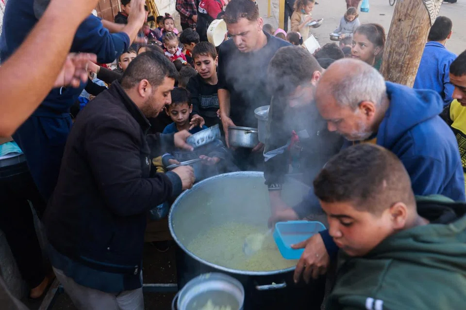 DILANDA KELAPARAN: Penduduk Palestin mengambil makanan di pusat pengagihan yang dikelolakan sebuah badan amal di Rafah, selatan Gaza.