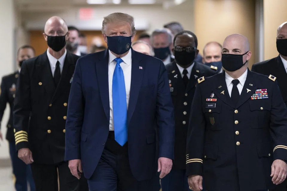 MENJADI CONTOH: Encik Trump memakai pelitup muka berwarna hitam ketika beliau berjalan di koridor hospital tentera Walter Reed, di luar Washington bagi bertemu dengan askar yang cedera dan kakitangan perubatan Covid-19 di situ. - Foto EPA-EFA
