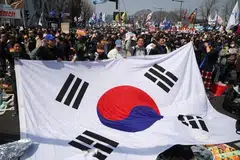 Orang ramai mengibarkan bendera Korea Selatan semasa mereka meraikan pemecatan Presiden Yoon Suk Yeol, dalam perhimpunan berhampiran Mahkamah Perlembagaan di Seoul pada 4 April.