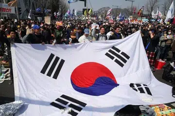 Orang ramai mengibarkan bendera Korea Selatan semasa mereka meraikan pemecatan Presiden Yoon Suk Yeol, dalam perhimpunan berhampiran Mahkamah Perlembagaan di Seoul pada 4 April.