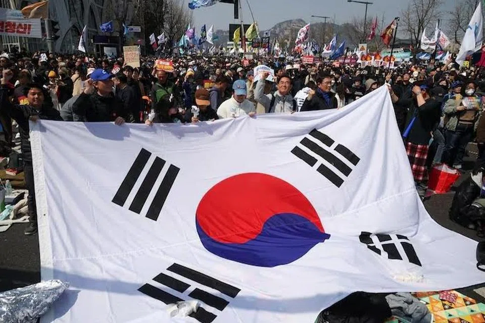 Orang ramai mengibarkan bendera Korea Selatan semasa mereka meraikan pemecatan Presiden Yoon Suk Yeol, dalam perhimpunan berhampiran Mahkamah Perlembagaan di Seoul pada 4 April.