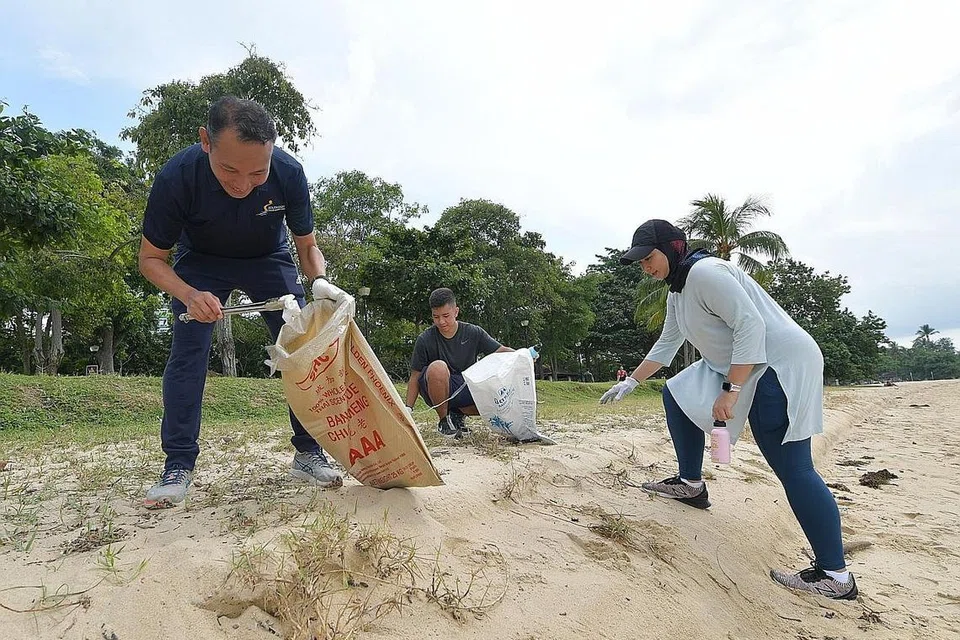BERSIHKAN PANTAI: Encik Mohd Fahmi Aliman (kiri) bersama relawan Sharifah Sheikha Haroon Aljunied dan anaknya, Encik Daniyal Rashad Mohammad Yusri, mengutip sampah di pantai East Coast semasa kegiatan membersihkan pantai anjuran CDC South East semalam. - BH oleh * ALPHONSUS CHERN