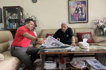 MENGHARGAI PERANAN BAPA: Penulis (kiri) meluangkan masa bersama bapanya, Hussaini Abdullah, membincangkan laporan berita yang menarik perhatian mereka. - Foto BM oleh CHAIRUL FAHMY HUSSAINI