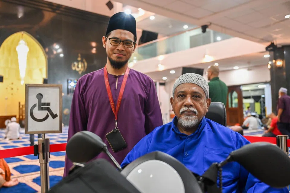 BERI PELUANG SAMA: Pengurus Masjid Al-Khair, Ustaz Muhammed Faheem Abdul Khalil (berdiri), mahu memberi peluang kepada pengguna kereta roda atau skuter elektrik seperti Encik Mohamed Ekball Packir Mohamed solat di saf hadapan.