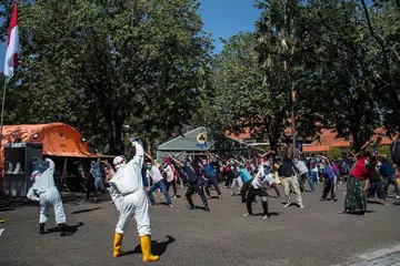 TANGANI VIRUS: Beberapa pekerja kesihatan sedang mengetuai senaman pagi buat pesakit di satu hospital di Surabaya yang dijangkiti Covid-19 namun tidak menunjukkan gejala serius. - AFP.
