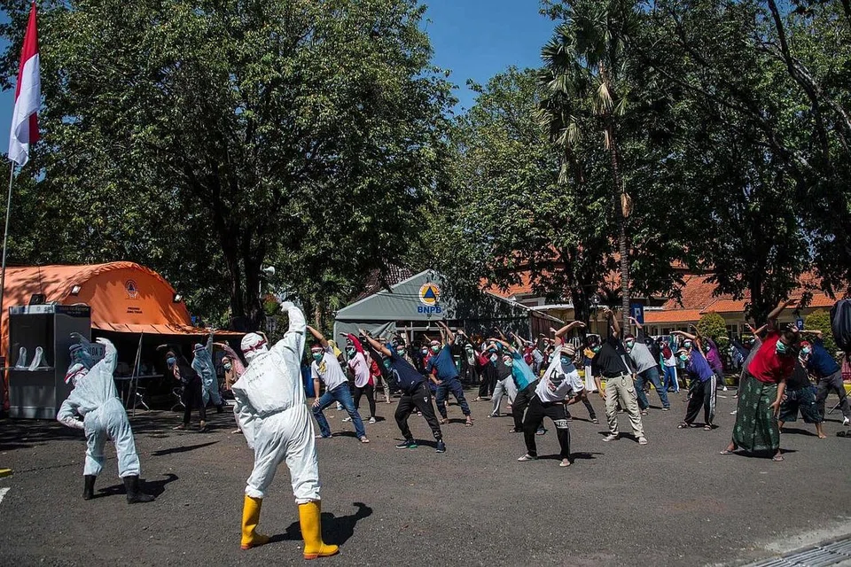 TANGANI VIRUS: Beberapa pekerja kesihatan sedang mengetuai senaman pagi buat pesakit di satu hospital di Surabaya yang dijangkiti Covid-19 namun tidak menunjukkan gejala serius. - AFP.