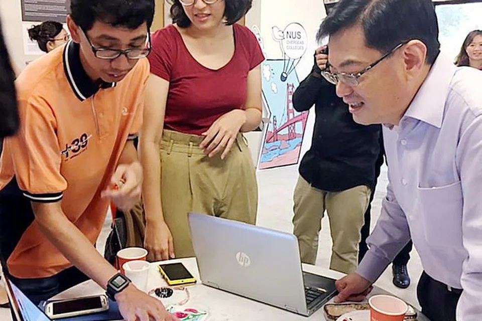 CIPTAAN MENARIK PERHATIAN: Encik Heng (kanan) mendapat penjelasan dari Encik Abdul Hadi Abdul Halim mengenai ciptaannya yang menggunakan teknologi mengecam wajah (Facetrax) di The Hangar di NUS. Di tengah ialah Cik Sarah Ho yang juga mencipta produk dikenali sebagai Anonymous Chat. - Foto NORHAIZA HASHIM