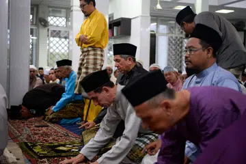 SUASANA PAGI RAYA DI MASJID: Dr Yaacob Ibrahim (empat dari kanan) dan Encik Mohd Alami Musa (tiga dari kanan) kelihatan sedang menunaikan solat sunat sebelum bermulanya solat Hari Raya di Masjid Ar-Raudhah kelmarin. - Foto THE STRAITS TIMES