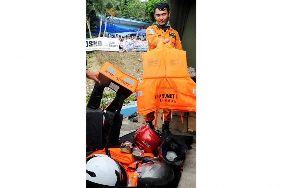 MILIK PENUMPANG: Pegawai penyelamat membawa barangan yang dipercayai milik mangsa feri karam di Danau Toba di Pelabuhan Tigaras, Simalungun, Sumatra. - Foto AFP