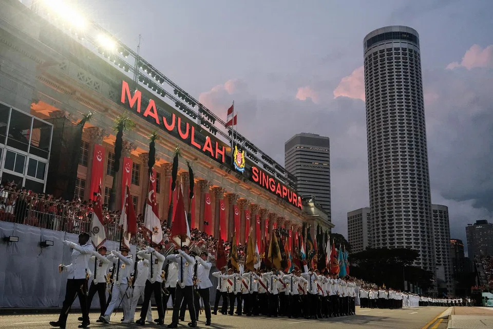 KAWALAN KEHORMATAN: Kontingen bendera dan kawalan kehormatan  berbaris keluar dari Padang di depan Galeri Nasional Singapura.