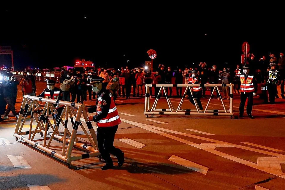 SEKATAN DIKETEPIKAN: Kakitangan keselamatan di stesen tol keluar masuk Wuhan mengetepikan hadangan di jalan raya pada Rabu lalu setelah perintah sekatan di Wuhan ditarik balik. - Foto REUTERS