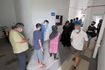 LANGKAH KESAN JANGKITAN: Penduduk Blok 91 Henderson Road beratur bagi ujian swab Covid-19 di sebuah ruang umum berdekatan semalam. - Foto BH oleh GAVIN FOO