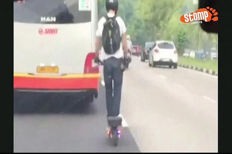 TINDAKAN MENGGADAI NYAWA: Seorang penunggang skuter elektronik dirakam merentasi lorong kiri untuk masuk ke lorong tengah lalu memotong sebuah bas SMRT. Tindakannya yang berbahaya ini dirakam dari sebuah kereta di kawasan Mandai Road. - Foto STOMP