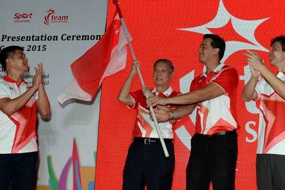KIBARAN PENUH SEMANGAT: Kededua chef-de-mission kontinjen Singapura, Dr Tan Eng Liang (dua dari kiri) dan Encik Nicholas Fang, mengibarkan bendera negara sebaik sahaja menerimanya daripada Encik Tan Chuan-Jin (kiri) dalam upacara malam tadi. Turut menyerikan majlis semalam ialah Encik Lawrence Wong. - Foto ZAINAL YAHYA