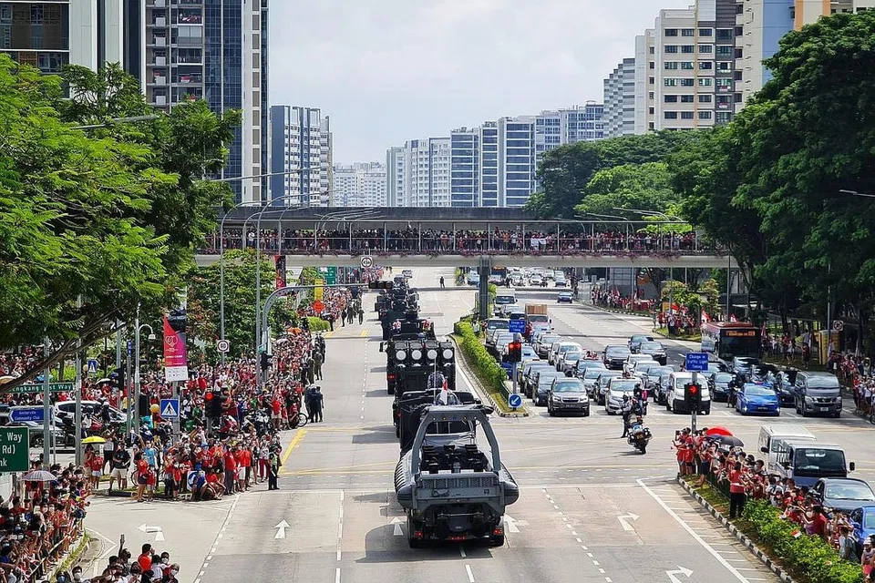 DIBAWA LEBIH DEKAT KEPADA PENDUDUK: Orang ramai bersorak apabila kontinjen Perarakan Kenderaan melalui Sengkang East Road berdekatan Hospital Besar Sengkang semalam. - Foto BH oleh KELVIN CHNG 