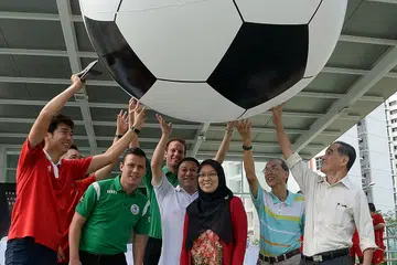 SUKAN PEMBAKAR SEMANGAT: Dr Intan (tengah) dan Pengarah Ark Sports Management Pte Ltd, Encik Beh (paling kiri), berharap belia berisiko dan kanak-kanak kurang berkemampuan dapat meraih motivasi diri menerusi Biasiswa Latihan Bola Sepak yang bakal dikenalkan. Bersama mereka di pembukaan semula Hab Sukan Buangkok ialah pemimpin akar umbi dan jurulatih bola sepak dari Belanda. - Foto JOHARI RAHMAT