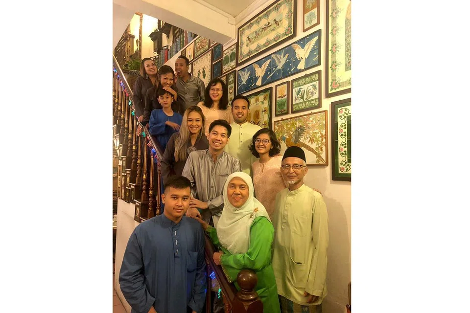 AKTIF SEBAGAI ANGGOTA KELAB JAGA CUCU: Encik Imran (paling kanan, di depan) dan isterinya, Cik Jamaliah (di sebelahnya, berbaju kurung hijau), bergambar bersama anak-anak dan cucunya di rumah mereka di Bedok. - Foto ihsan IMRAM MOHAMED