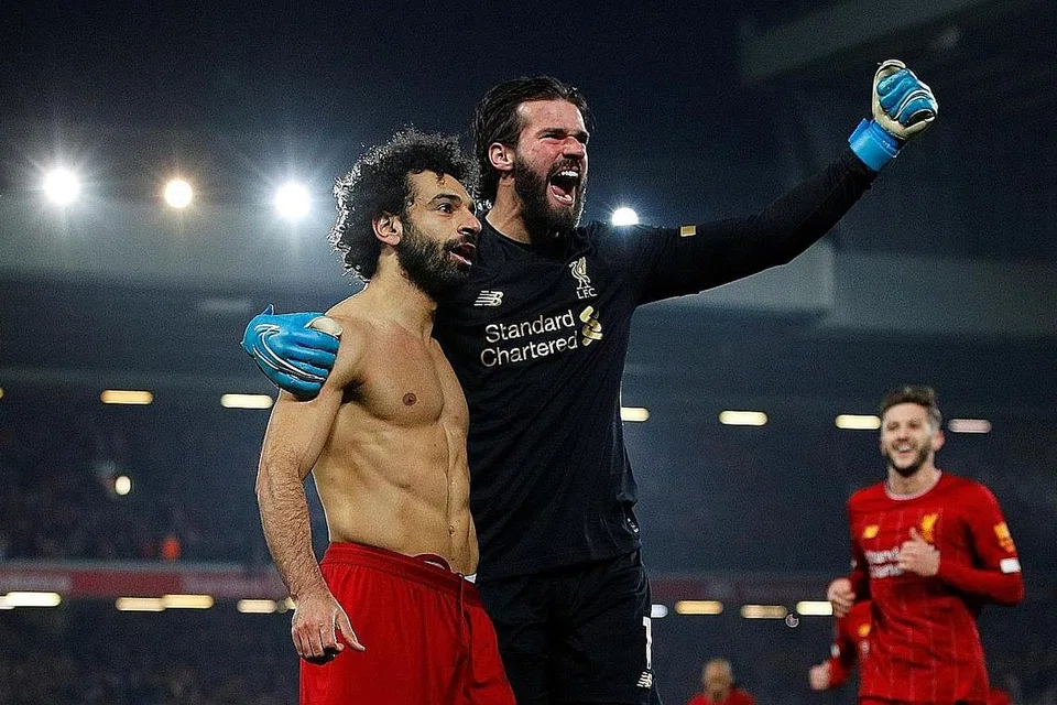 TERUS MAJU: Mohamed Salah merayakan gol kedua Liverpool dengan Alisson dalam kemenangan 2-0 ke atas Manchester United di Anfield. Liverpool kini 16 mata di hadapan pencabar terdekat. - Foto REUTERS