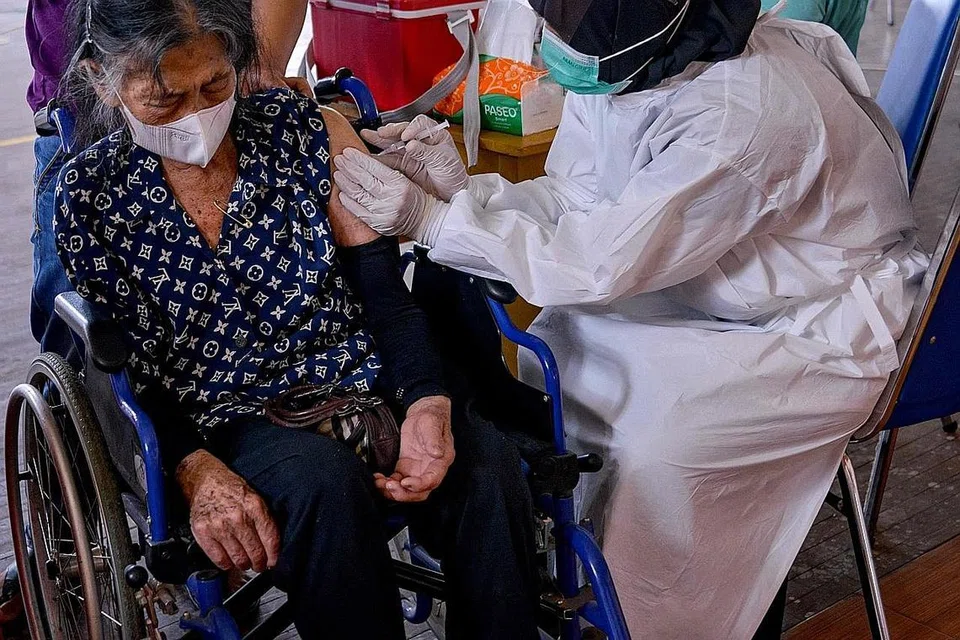 VAKSINASI: Seorang warga emas menerima vaksin Sinovac di Banda Aceh, Indonesia. Dengan lebih dua juta kes Covid-19, Indonesia kini berdepan dengan lonjakan jangkitan selepas lebih sebulan sambutan perayaan Aidilfitri. - Foto AFP