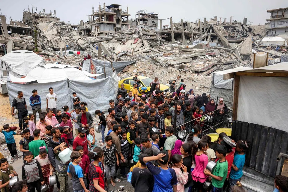 Orang ramai beratur sambil membawa periuk untuk menerima makanan amal daripada sebuah dapur bantuan di Beit Lahia, utara Semenanjung Gaza pada 24 April 2025. Israel telah menyambung semula serangan ketenteraan secara besar-besaran di wilayah Palestin pada 18 Mac, selepas perjanjian gencatan senjata yang dimeterai pada 19 Januari runtuh dua bulan kemudian akibat perbezaan pendapat mengenai fasa rundingan yang seterusnya.