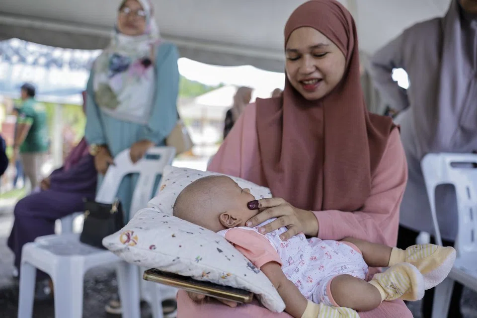 BAWA ANAK BERSAMA: Siti Aisyah Azizan, 30 tahun, membawa bayinya Muhammad Aryan Muhamad Nur Izhar untuk menunaikan tanggungjawab sebagai pengundi di Pusat Mengundi Sekolah Kebangsaan Bandar Baru Beris Jaya bagi Dewan Undangan Negeri (DUN) Jeneri, Kedah, pada Sabtu.