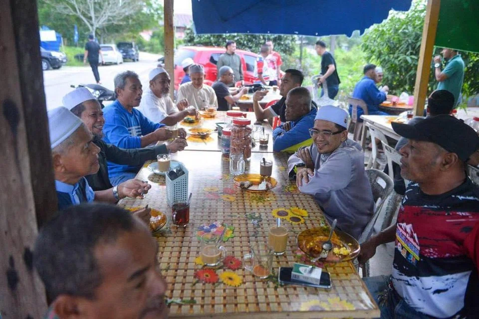 Calon Barisan Nasional (BN), Encik Mohd Azmawi Fikri Abdul Ghani (duduk, dua dari kanan), menyantuni pengundi sempena kempen pilihan raya kecil Dewan Undangan Negeri Nenggiri, di Gua Musang, Kelantan.