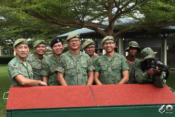 Leftenan Kolonel (LTC) Mohammad Faizal Amat (tiga dari kanan) berdiri di belakang rekaan Bay Kursus Ketepatan Jarak Jauh (DAC) Mudah Alih yang telah menerima penghargaan Anugerah ‘Dare to Do’ Kementerian Pertahanan (Mindef) pada 23 Julai. Bersama beliau dalam menjayakan rekaan tersebut adalah (dari kiri) Pegawai Waran Kanan (SWO) Lim Cheng Yong, Pegawai Waran Pertama (1WO) Muhammad Hasyim Hassan, Pegawai Waran Pertama (1WO) Vincent Teo, Pegawai Waran Kedua (2WO) Tan Eng Tat, Pegawai Waran Kedua (2WO) Shaun Lim, Sarjan Pertama (1SG) Sriram Saravanan dan Sarjan Ketiga (3SG) Mohamed Shakir Mohamed Sheriff, seorang anggota Perkhidmatan Negara Sepenuh Masa (NSF).