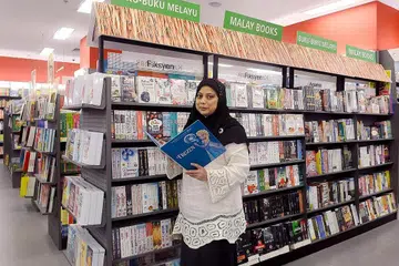 ANEKA JENIS BUKU MELAYU: Buku-buku Melayu yang merangkumi buku masakan, fiksyen, agama dan kanak-kanak kini boleh didapati di tiga lagi cawangan kedai buku Popular di gedung Bedok Mall, Causeway Point dan Jurong Point selain gedung One KM. Gambar menunjukkan Cik Rokiah Rajib, pegawai promosi produk di kedai buku Popular di bahagian buku Melayu di gedung One KM. - Foto TAUFIK A. KADER